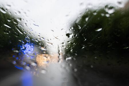 Raindrops on a windscreen glass with a blurred night city lights at the background.の写真素材