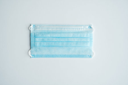 Face medical mask on a gray background. Disposable 3-ply medical mask to cover the mouth and nose to...