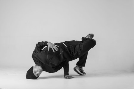 A man hip hop dancer or bboy freezes in one pose on a white background. Bboy doing stylish stunts.