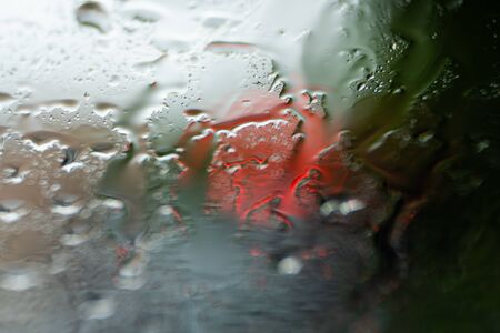 Blurred raindrops on a windscreen glass with a night city lights at the background.の写真素材