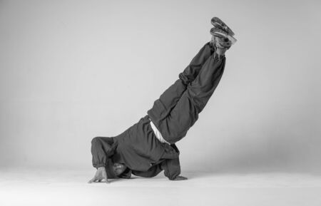 A man hip hop dancer or bboy freezes in one pose on a white background. Bboy doing stylish stunts.の写真素材