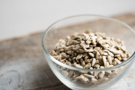 Sunflower seeds in a small plate on the wooden vintage table. Healthy vegetarian protein nutritious...