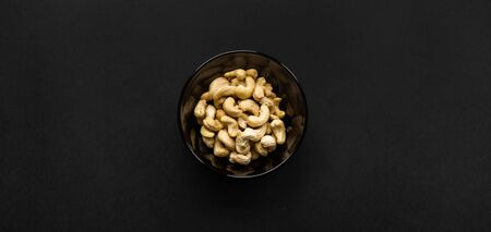 Cashew nuts in a small plate on a black table as a background. Cashew nut is a healthy vegetarian protein nutritious food.の写真素材