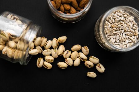 Pistachio scattered on the black table from a jar. Walnut is a healthy vegetarian protein nutritious food.の写真素材