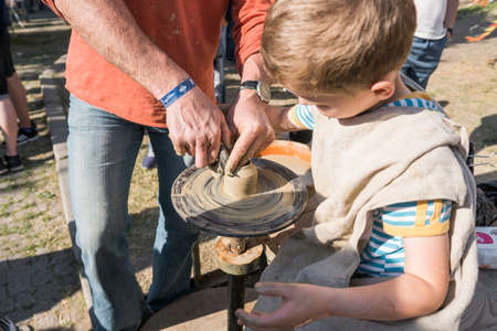 UKRAINE, LUTSK - June 5, 2019: The hands of an adult man teaching pottery the child how to make a jug from a piece of clay on a Potter's wheelのeditorial素材