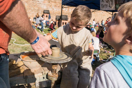 UKRAINE, LUTSK - June 5, 2019: The hands of an adult man teaching pottery the child how to make a jug from a piece of clay on a Potter's wheelのeditorial素材