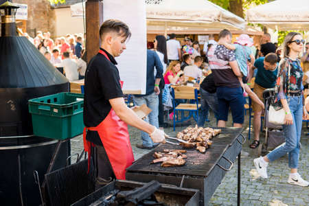 UKRAINE, LUTSK - June 5, 2019: Man is cooking a meat on a grill on a food fest.のeditorial素材