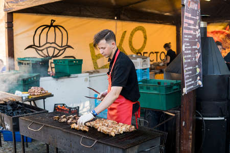 UKRAINE, LUTSK - June 5, 2019: Man is cooking a meat on a grill on a food fest.のeditorial素材