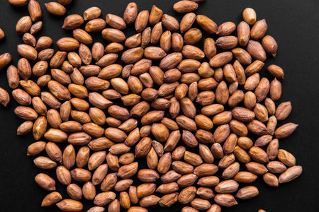 Peanut nuts scattered on a black table. Peanuts nut is a healthy vegetarian protein nutritious food