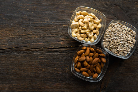 Almond, sunflower seeds and cashew in a small plates which standing on a vintage wooden table. Nuts...