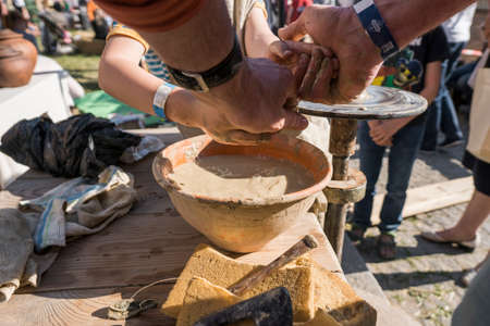 UKRAINE, LUTSK - June 5, 2019: The hands of an adult man teaching pottery the child how to make a jug from a piece of clay on a Potters wheel on a food fest.のeditorial素材