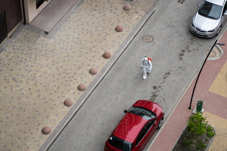 UKRAINE, KYIV - May 20, 2020: Man in a white protective suit and mask is walking on a street for...