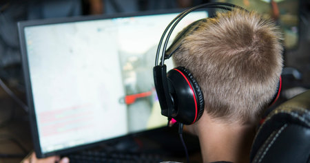 POLAND, WARSAW - June 10, 2020: Back view of young gamer in headphone playing video game at computer...