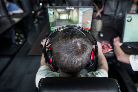 POLAND, WARSAW - June 10, 2020: Back view of young gamer in headphone playing video game at computer...