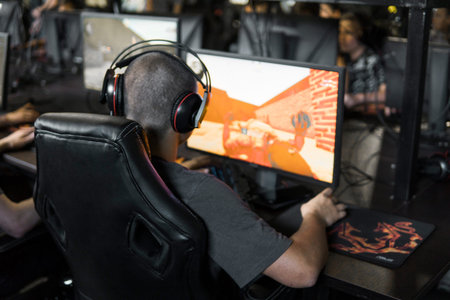 POLAND, WARSAW - June 10, 2020: Back view of young gamer in headphone playing video game at computer...
