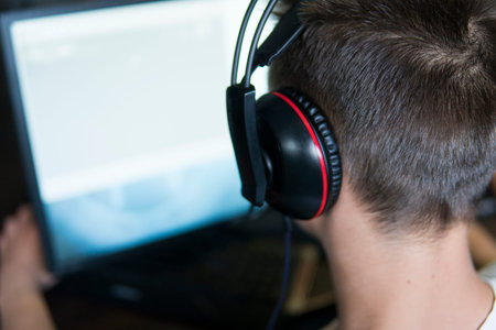 POLAND, WARSAW - June 10, 2020: Back view of young gamer in headphone playing video game at computer...