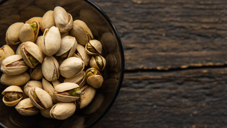 Pistachios in a small plate on a vintage wooden table. Pistachio is a healthy vegetarian protein...