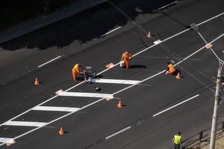 Road workers painting marking white line on the road surface. Thermoplastic spray marking machine...