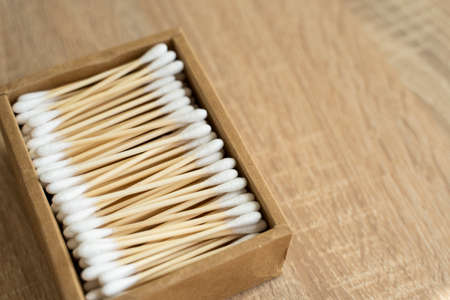 Eco-friendly cotton swabs. A cardboard box containing recyclable bamboo cotton buds on a table. Zero waste concept. Eco product. Cosmetic sticks in a box. Wooden sticks for cleaning ears.の写真素材
