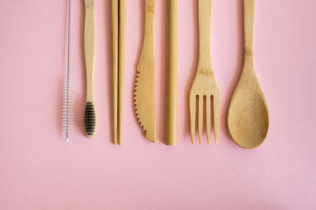 Eco friendly bamboo cutlery set in a case on a pink background. Zero waste concept. Set of bamboo cutlery in a case on a laying on a table. Spoon, fork, knife, toothbrush, tube and chinese sticks.の写真素材