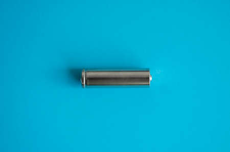 A single rechargeable battery on blue background. Silver alkaline AA battery for different device. Energy.の写真素材