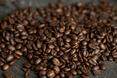 Roasted arabica coffee beans scattered on a wooden table. Fresh coffee beans.