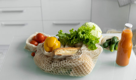 Eco friendly canvas grocery bag. Vegetables, fruits in reusable eco cotton bags and orange juice in...
