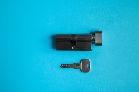 A door lock cylinder core with key on the blue background. The cylinder of the lock with key....