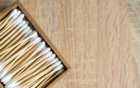 Eco-friendly cotton swabs. A cardboard box containing recyclable bamboo cotton buds on a table. Zero waste concept. Eco product. Cosmetic sticks in a box. Wooden sticks for cleaning ears.の写真素材