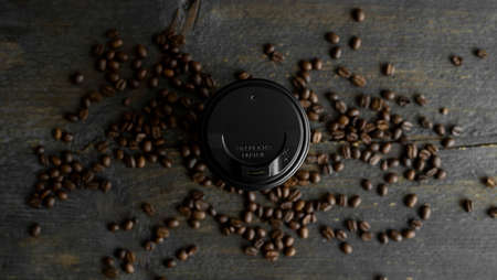 Paper cup of coffee with roasted coffee beans on wooden table background. Mug of black coffee.の写真素材