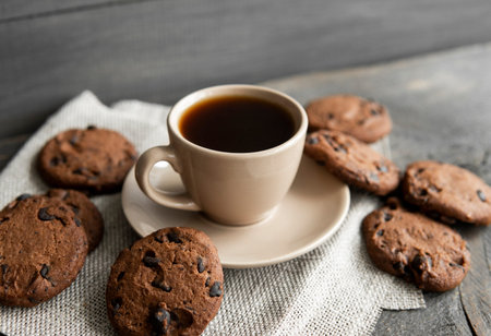 Coffee cup with cookies on wooden table background. Mug of black coffee with chocolate cookies....