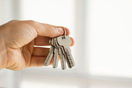 Mens hand holding a set of keys. Realtor is giving the keys to an apartment to clients. Focus on the...