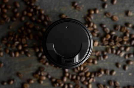 Paper cup of coffee with roasted coffee beans on wooden table background. Mug of black coffee.の写真素材