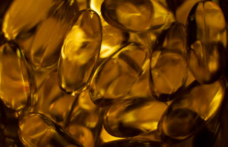 Extreme close up of fish oil orange yellow softgels capsules fish oil omega 3 or omega 6, omega 9, vitamin A, vitamin D, vitamin E background. Healthy vitamins product concept.の写真素材