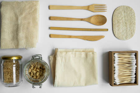 Zero waste kit. Set of eco friendly bamboo cutlery, mesh cotton bags, glass jars with a nuts, loofah sponge and box of cotton swabs. Natural and reusable items accessories on gray surface.の写真素材