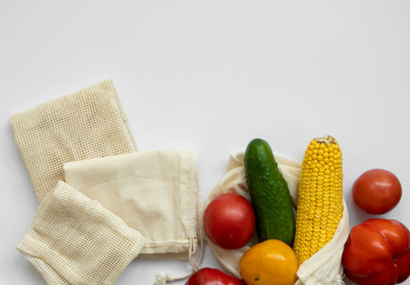 Bunch of mixed organic vegetables and empty reusable cotton bag on a table. Zero waste concept. Eco...