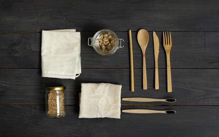Zero waste kit. Set of eco friendly bamboo cutlery, mesh cotton bags, bamboo toothbrush and glass jars. Plastic free. Natural and reusable items accessories on wooden table surface.の写真素材