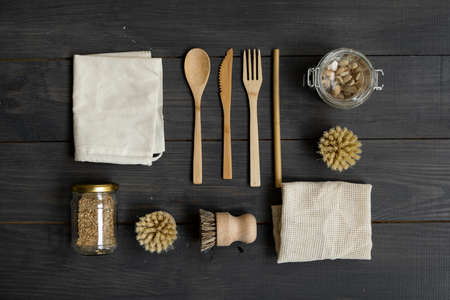 Zero waste kit. Set of eco friendly bamboo cutlery and cleaning brushes, mesh cotton bags and glass jars. Plastic free. Natural and reusable items accessories on wooden table surface.の写真素材