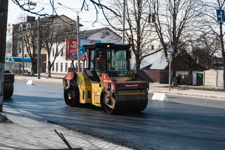 KYIV, UKRAINE - September 10, 2020: Heavy asphalt road roller with heavy vibration roller compactor that press new hot asphalt on the roadway on a road construction site on a street.のeditorial素材