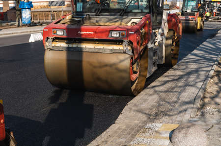 KYIV, UKRAINE - September 10, 2020: Heavy asphalt road roller with heavy vibration roller compactor that press new hot asphalt on the roadway on a road construction site on a street.のeditorial素材