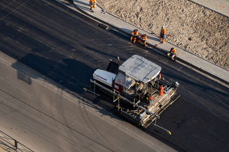 KYIV, UKRAINE - September 10, 2020: Industrial asphalt paver machine laying fresh asphalt on road construction site on the street.のeditorial素材