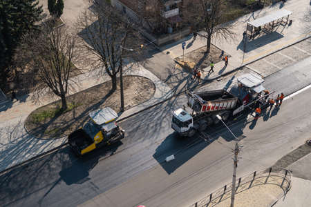 KYIV, UKRAINE - September 10, 2020: Industrial asphalt paver machines laying fresh asphalt on road construction site on the street.のeditorial素材