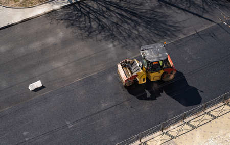 Asphalt road roller with heavy vibration roller compactor press new hot asphalt on the roadway on a road construction site. Heavy Vibration roller at asphalt pavement working. Repairing.の写真素材