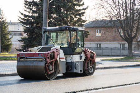Asphalt road roller with heavy vibration roller compactor press new hot asphalt on the roadway on a road construction site. Heavy Vibration roller at asphalt pavement working. Repairing.の写真素材