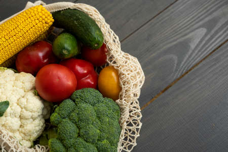 Bunch of mixed organic vegetables in reusable cotton mesh bag on a table. Zero waste concept. Eco friendly lifestyle concept. Groceries in eco bags. Plastic free items. Reuse, reduce, recycle, refuse.の写真素材