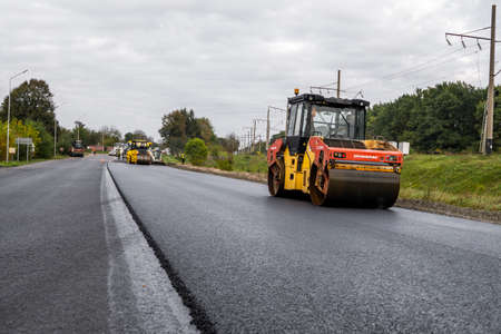 KYIV, UKRAINE - September 25, 2020: Two heavy asphalt road roller with heavy vibration roller compactor that press new hot asphalt on the roadway on a road construction site on a street.のeditorial素材