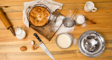 Tasty apple pie on a oaken wood table with a ingredients. Cooking a delicious apple pie on a kitchen...