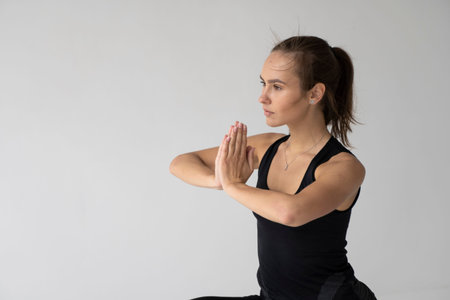 Young woman is practicing yoga in a studio. Slim young girl in a black sport wear is doing yoga...