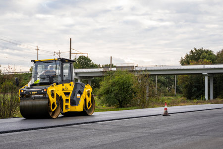 KYIV, UKRAINE - September 25, 2020: Heavy yellow asphalt road roller with heavy vibration roller compactor that press new hot asphalt on the roadway on a road construction site on a street.のeditorial素材