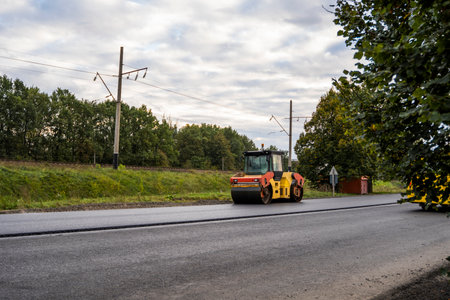 KYIV, UKRAINE - September 25, 2020: Heavy yellow asphalt road roller with heavy vibration roller compactor that press new hot asphalt on the roadway on a road construction site on a street.のeditorial素材